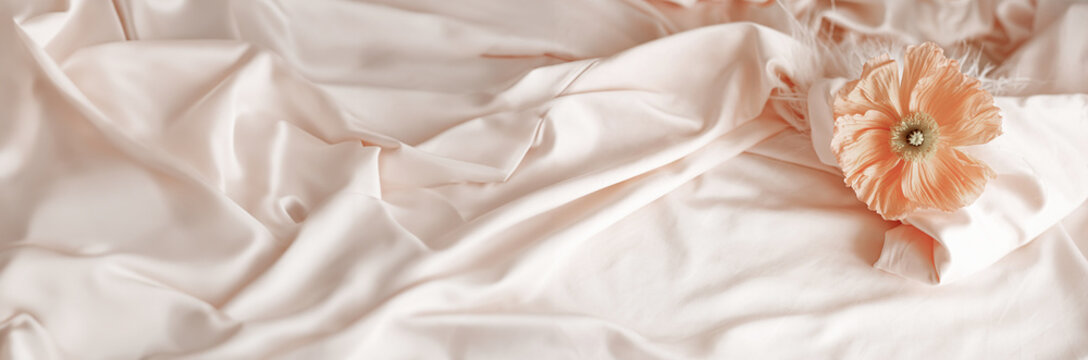 Orange ranunculus on pink silk satin fabric top view