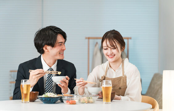 マイホームのダイニングテーブルで食事,晩酌をする若いアジア人夫婦,カップル