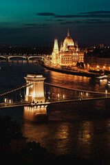 Fototapeta premium The illuminated Hungarian Parliament Building and Chain Bridge reflected on the Danube River after sunset.