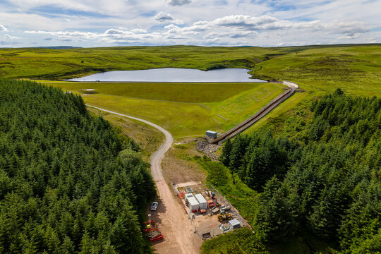Looking down at a scenic water reservoir and dense green pine forest