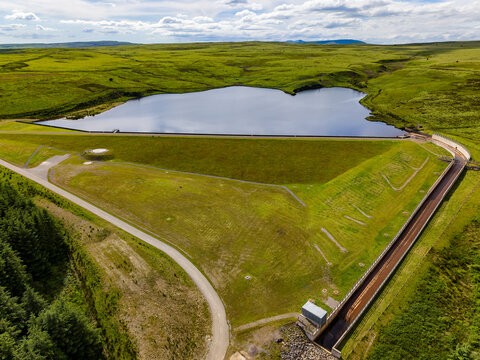 Viewing a scenic water reservoir and green hills from above on a sunny day