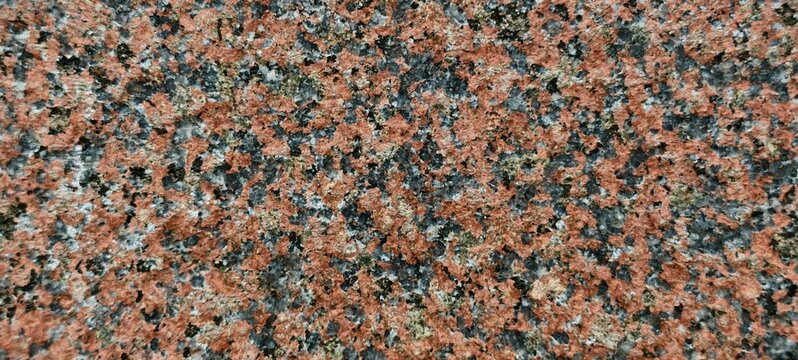 Close-up of a polished granite slab showcasing a speckled crystalline pattern of pink feldspar, gray quartz, and black biotite. The coarse-grained igneous texture emphasizes natural color variation.