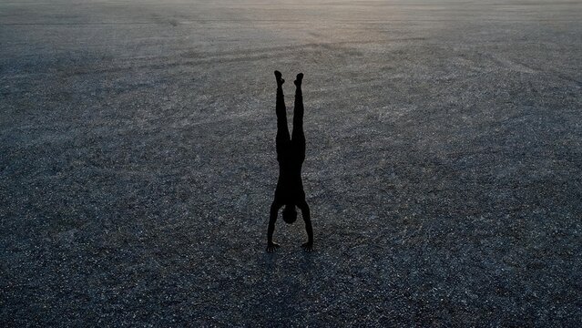 Silhouette of person doing handstand