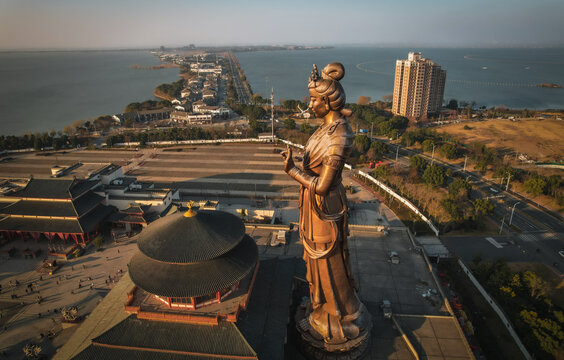 Aerial view of the bronze Guanyin statue at Chongyuan Temple overlooking Jinji Lake, with traditional architecture, paved courtyards, and trees in Suzhou, Jiangsu, China.