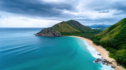 Fototapeta premium A breathtaking aerial view of a pristine tropical beach with turquoise waters meeting a sandy shore, bordered by lush green hills under a dramatic cloudy sky