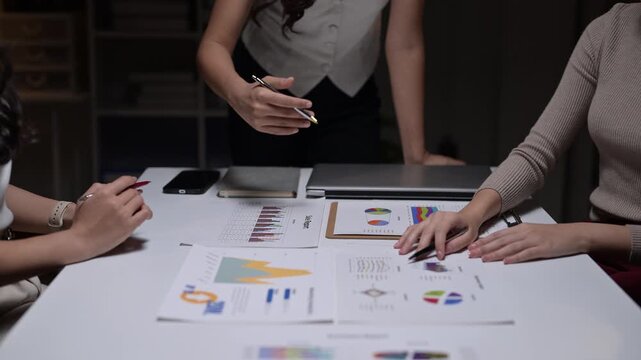 Businesswomen working late analyzing financial charts