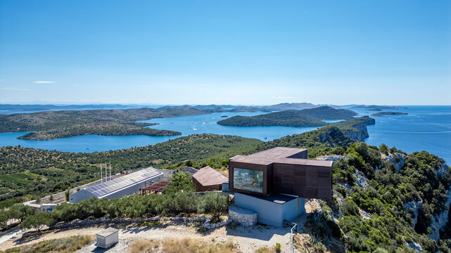 Aerial view of the modern visitor center in Telasica Nature Park, surrounded by olive groves and rocky landscape overlooking the Adriatic Sea and islands in Sali, Zadar County, Croatia.