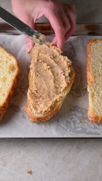 Almond croissant halves filled with almond frangipane cream using spatula on parchment lined baking tray. Pastry preparation video. Bakery, dessert and homemade baking concept.