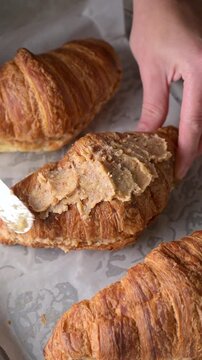 Almond pieces sprinkled on almond croissants with frangipane cream on parchment lined baking tray before baking. Pastry preparation video. Bakery, dessert and homemade baking concept.