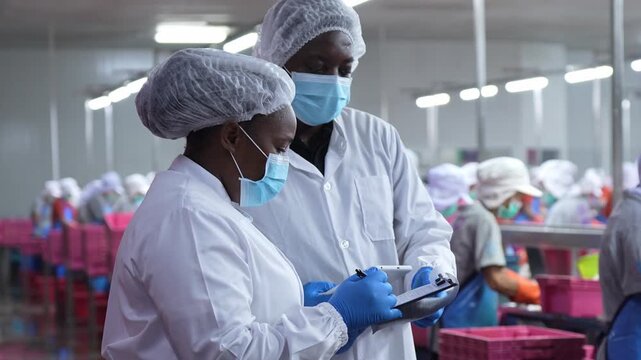 Team of Quality control inspectors in protective gear checking food production line, Diverse industrial team conducting safety audit at a food processing plant