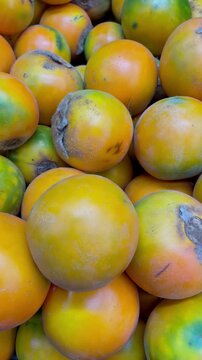 Close up full frame texture of fresh ripe lulo fruits pile or naranjilla exotic tropical fruit at market display