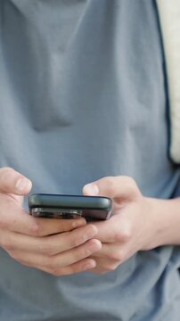 Close up of teenager hands holding and typing on smartphone. Vertical shot of concept of mobile chat, social media use, digital communication, screen time, texting habit and modern youth lifestyle.