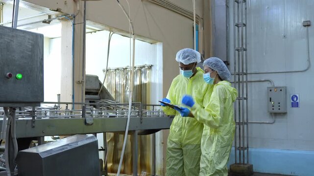 Food safety inspectors checking metal cans in canning production line, Quality assurance team inspecting canned food in manufacturing plant, Technical with clipboard working in sterile food factory