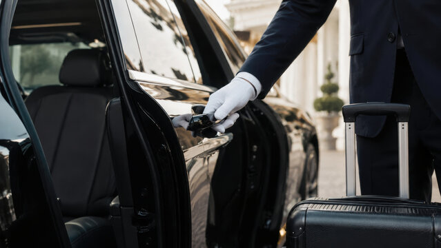 Vip travel arrangements luxury chauffeur service with elegant driver opening car door for business passenger hotel entrance luggage ready for ride