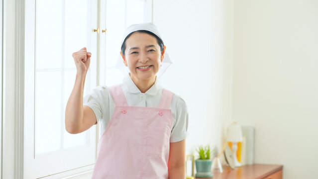 ガッツポーズするエプロンをつけたミドル女性