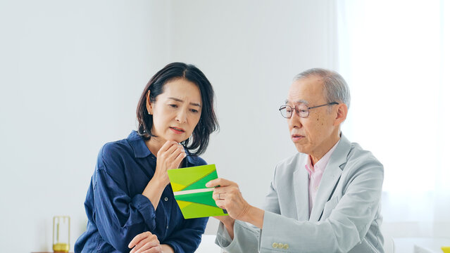 通帳を見ながら相談する女性とシニア男性