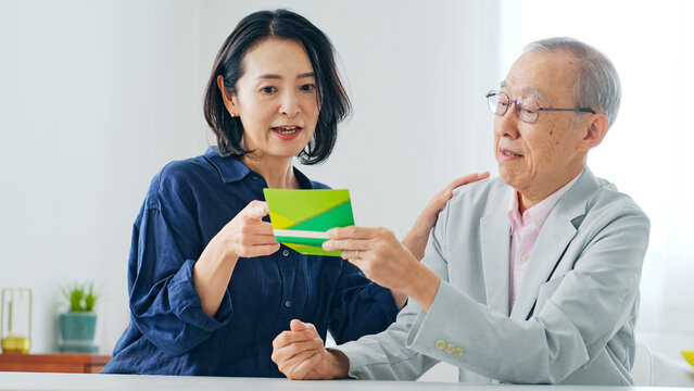 通帳を見てお金をねだる女性とシニア男性