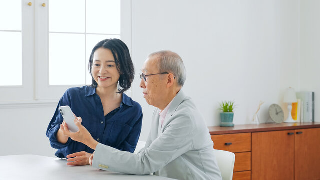スマホを見る女性とシニア男性