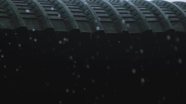 Close up video of heavy rain drops falling down from a dark corrugated rooftop during a stormy day