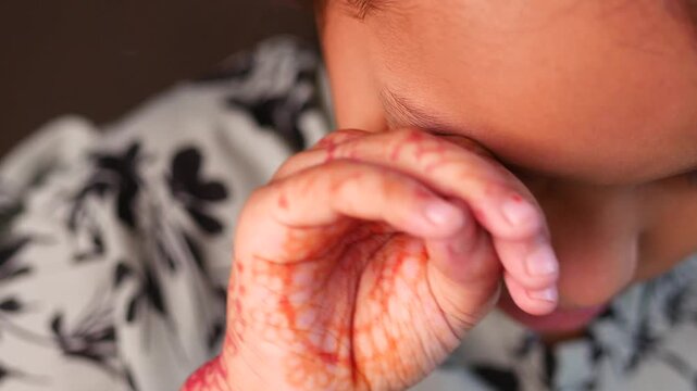 Little girl with traditional henna patterns on her hands rubbing her eyes in slow motion cinematic clip