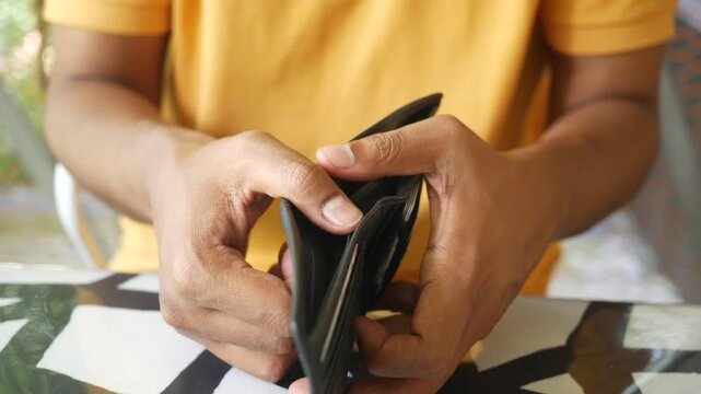 Man shows empty wallet to reveal no money inside for financial hardship concept
