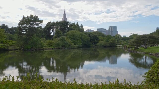 Shinjuku Gyoen National Garden Pond With NTT Docomo Yogogi Building In The Background In Tokyo, Japan. - wide static shot