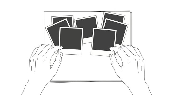A pair of hands arranging several blank polaroid photos on a flat surface.