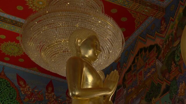 Golden Buddha Statue Beneath Large Crystal Chandelier Inside Wat Paknam Khaem Nu In Chanthaburi, Thailand. close-up, low angle shot