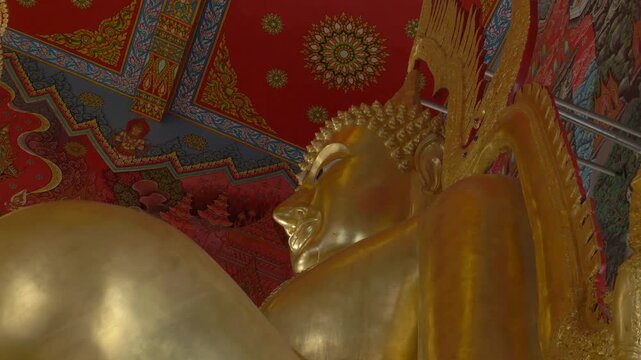 Close-Up Of Golden Buddha Statue Against Ornate Red And Gold Ceiling Inside Wat Paknam Khaem Nu In Chanthaburi, Thailand. low angle shot