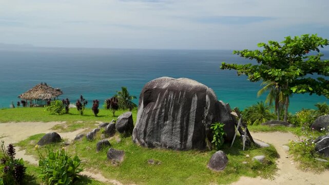 Orbital aerial around Bato ni Ningning granite boulders in San Vicente Palawan with lush green hillside viewpoint, ladder and sweeping coastal panorama