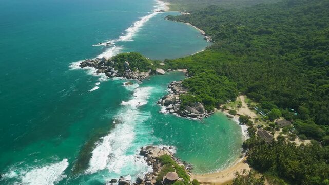 Aerial high altitude pullback above dramatic Cabo San Juan twin beaches with turquoise water rocky headlands and jungle coastline at Parque Tayrona Colombia