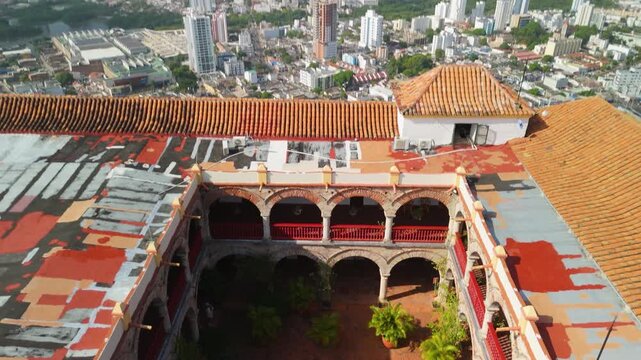 Aerial tilt up from arched cloister courtyard of La Popa convent revealing Cartagena cityscape skyline bay and Caribbean coast in Colombia with red tile rooftops below