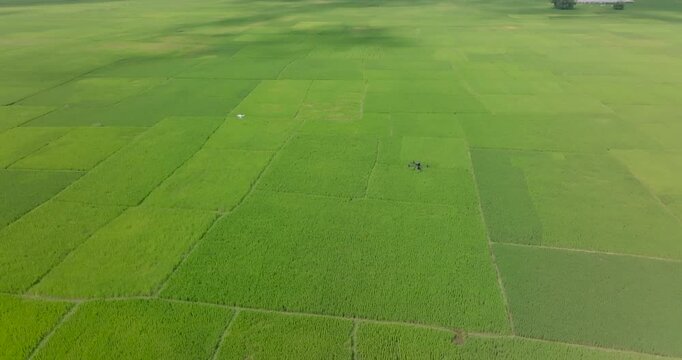 Koshi Nepal, static hovering drone shot capturing two drones mid-flight operating above vast green agricultural fields and flat Terai, lush grass plains, and cultivated farmlands