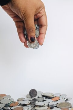 Dynamic motion shot of a single Malaysian coin bouncing on edge among a scattered pile of currency on a plain white background, symbolizing financial volatility, chance, or luck.