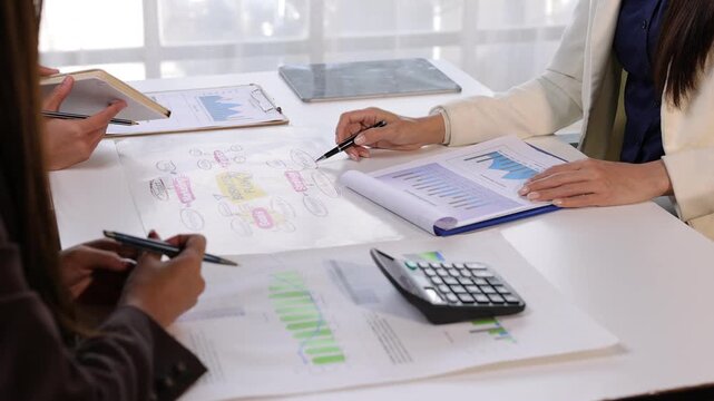 Business people are discussing and analyzing financial reports. Colleagues collaborating on a project, examining charts and diagrams in office.