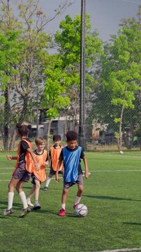 Two teams of kid football players competing during soccer game on sports field.