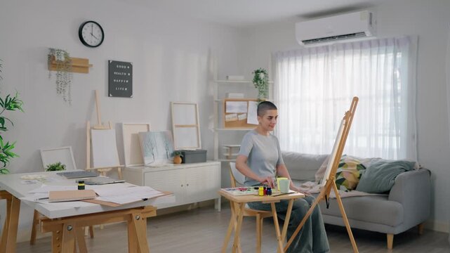 Caucasian female artist painting artwork on canvas frame at home studio. 