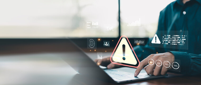 Cybersecurity warning concept with business professional using laptop and digital alert interface, representing risk management, data protection, threat detection, system security and compliance.
