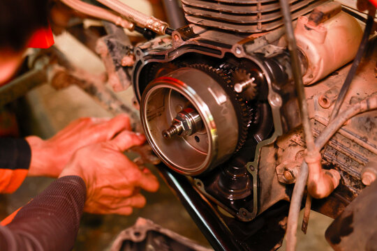 Motorcycle engine repair mechanic hand metal gear maintenance close up workshop technical machinery tool engineering mechanical part precision industrial dirty manual expertise skill fixing