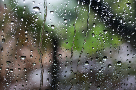 Raindrop water glass window nature blur wet weather transparent outdoor create peaceful mood as rain falls on window blurring green landscape outside and forming droplets and streaks on glass