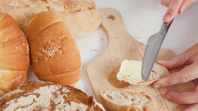 Hands Spreading Fresh Butter on Sliced Artisan Baguette