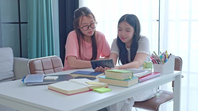 Two Asian girls using smartphone searching data for write report
