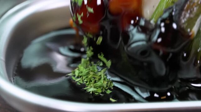 A high-quality close-up of a professionally plated Japanese seafood dish featuring buttery, pan-seared black cod (Gindara) or sea bass. The fish is served in a savory dark miso or soy-based broth, gar