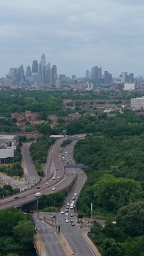 London skyline aerial tracking over the A12 toward central city, revealing the Shard, BT Tower and dense urban buildings under overcast summer skies. Vertical format for social media.