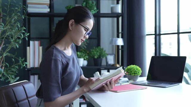 Beautiful Asian woman wear eyeglasses read book at home