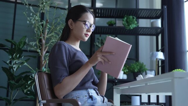 Beautiful Asian woman wear eyeglasses read book at home