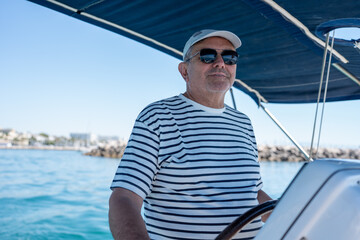 Fototapeta premium Senior man steering sailing boat enjoying summer vacation