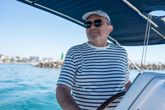 Senior man steering sailing yacht on summer vacation