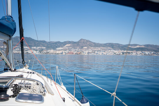 Sailboat cruising calm blue sea along city coast