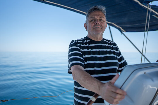 Mature man steering sailing yacht on calm ocean